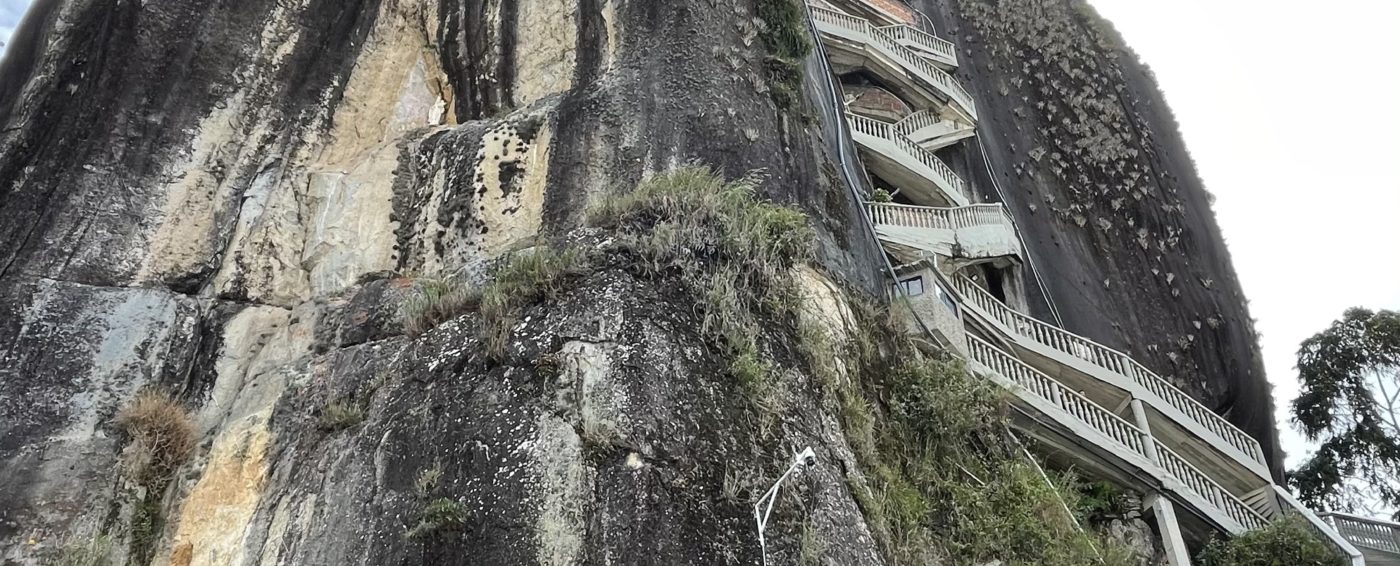 Ground view of El Penol Rock and entrance building with stair case leading to top in Guatape, Columbia
