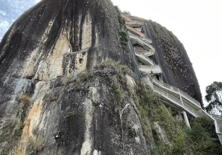 Ground View Of El Penol Rock Ground view of El Penol Rock and entrance building with stair case leading to top in Guatape, Columbia