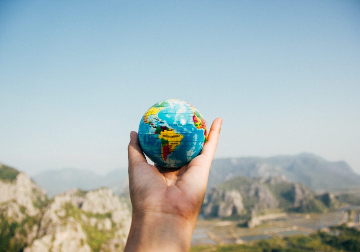 travel Holding up a small globe over beautiful landscape